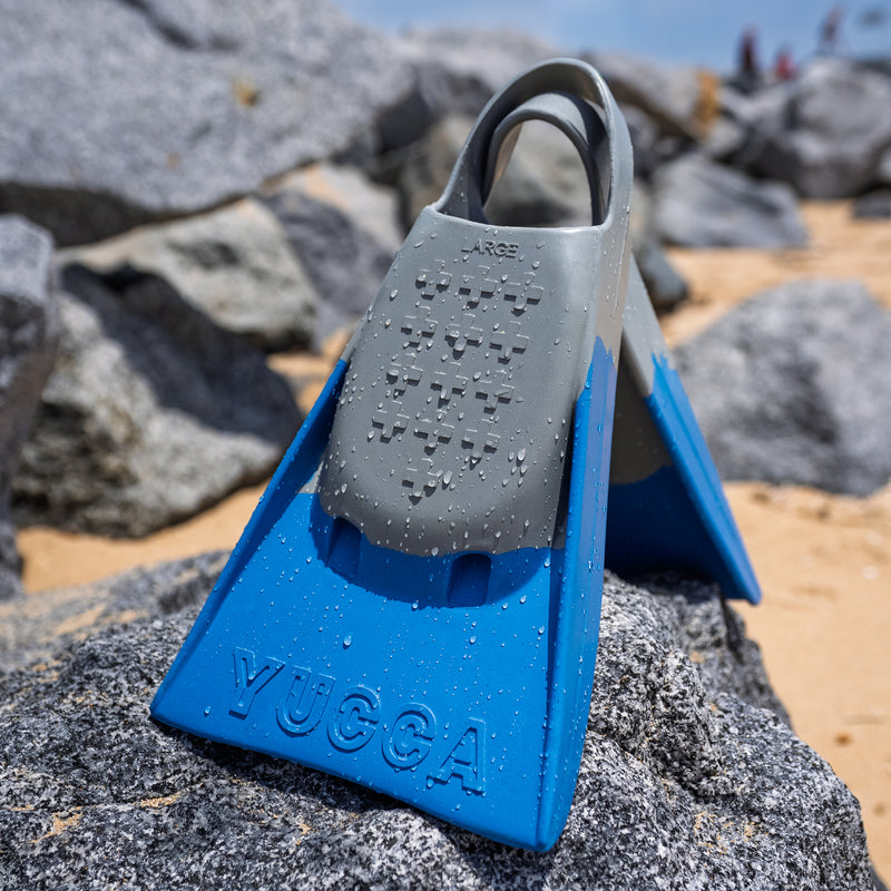 Yucca Solitude Short Blade Fins - Ultra Soft Flex - Yucca Fins on a rocky surface with a beach background