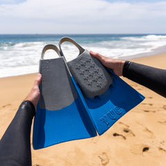 Person holding Yucca Solitude Short Blade Fins - Ultra Soft Flex - Yucca Fins with ocean and beach in the background