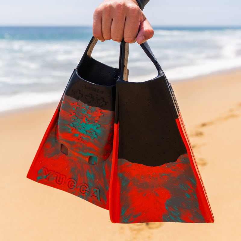 Yucca Sir Wiggins Short Blade Fins - Standard Flex - Yucca Fins held by a hand on a beach