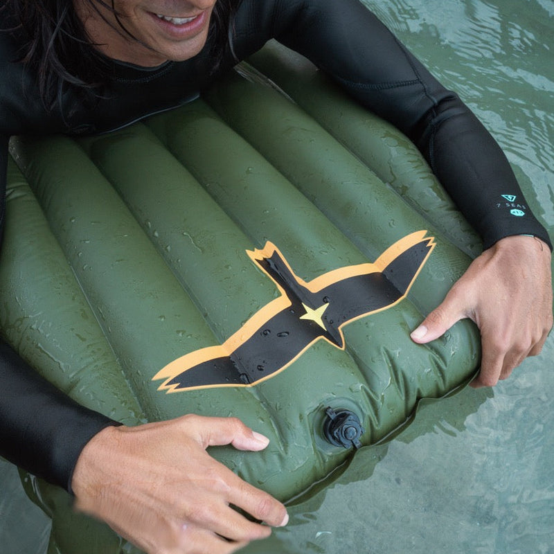 Person in a wetsuit on a surf mat in the water