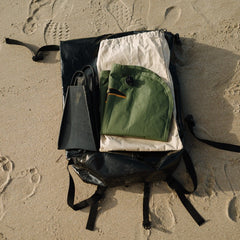 Deflated mini surf mat laying on a backpack next to a pair of black fins